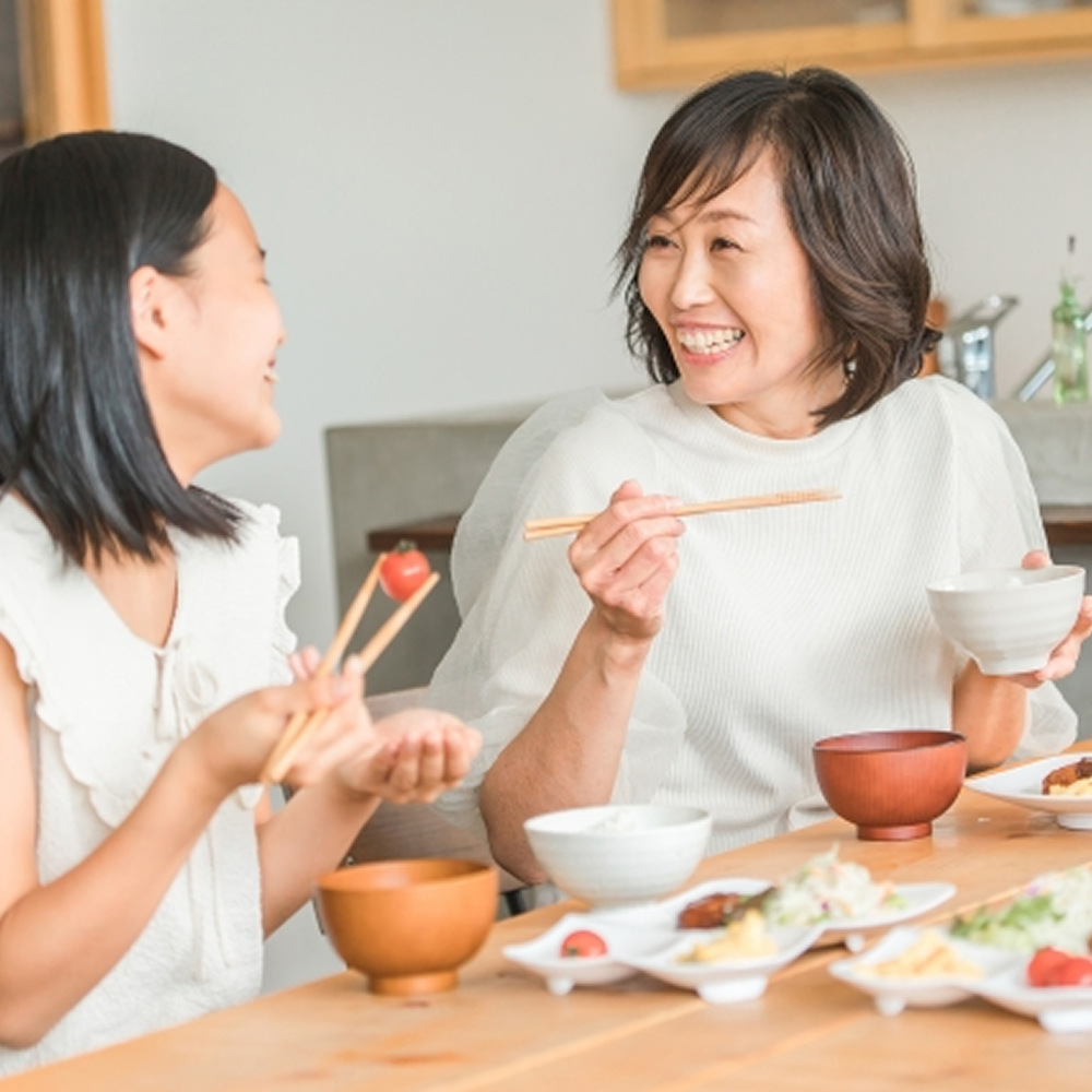 食卓で食事を楽しむ母と娘のイメージ画像